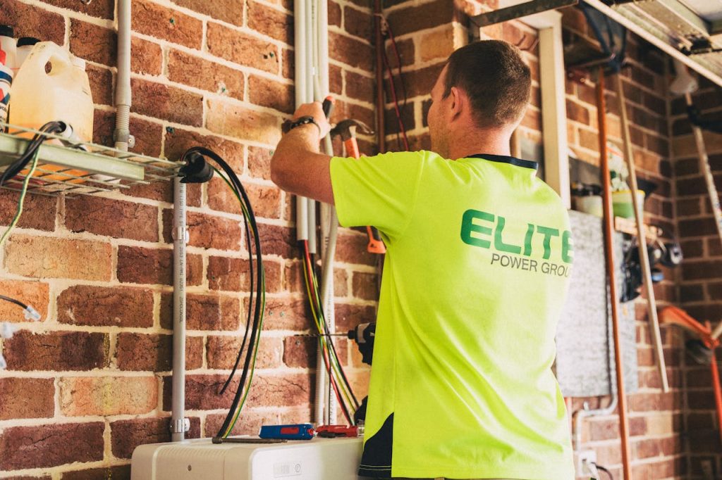 The Art of Drawing Readers In: Your attractive post title goes here Electrician performing solar battery installation for sustainable energy storage in a home setting.
