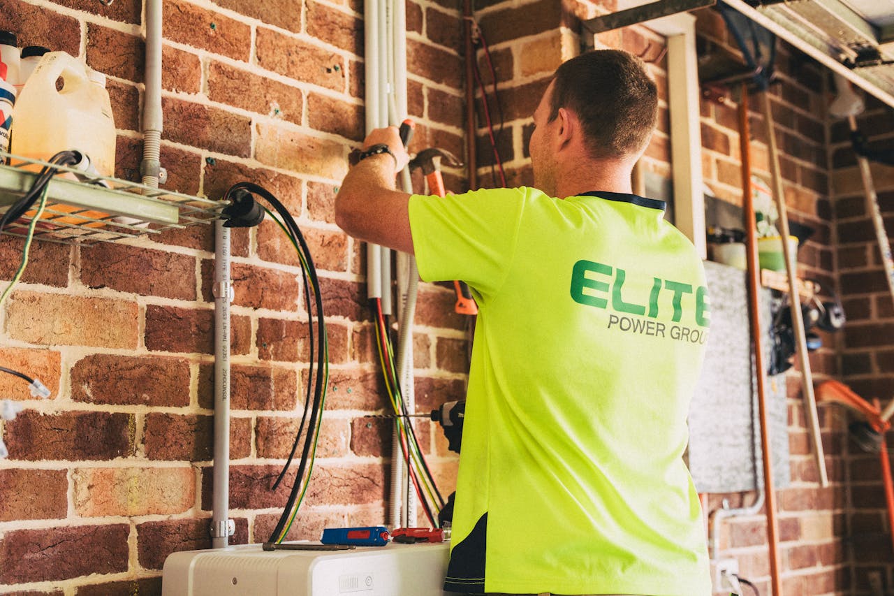 Electrician performing solar battery installation for sustainable energy storage in a home setting.